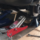 Compressing the spring required this janky arrangement of two jacks, a c-clamp, and a block of wood